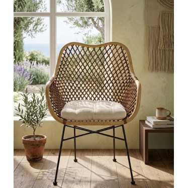 Fauteuil en osier design installé près d'une fenêtre dans une véranda