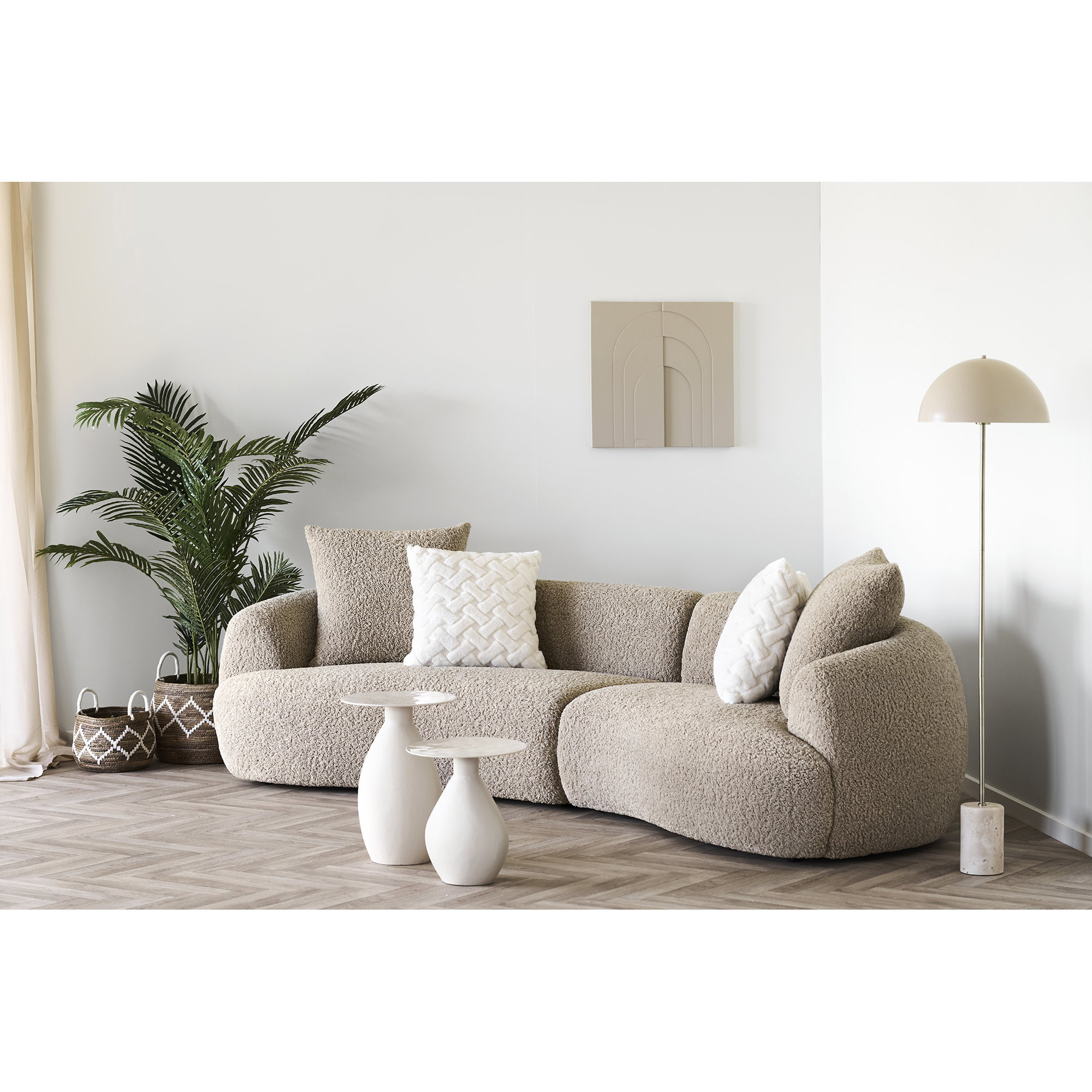 Canapé arrondi tissu beige Halden dans un salon lumineux avec plante