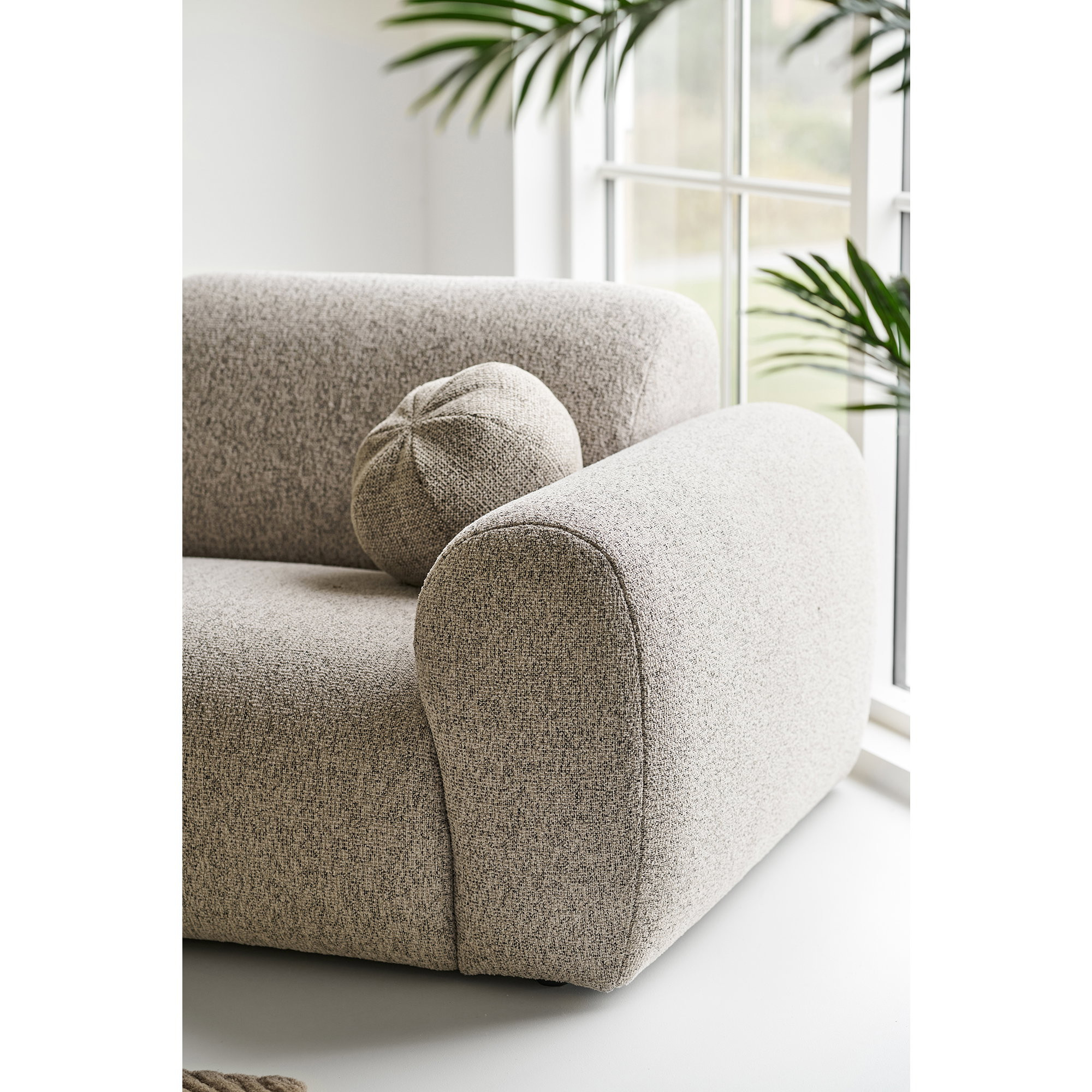 Vue en angle de l'accoudoir arrondi du canapé Zoltan en tissu gris